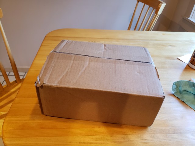 Closed cardboard box with no label. On a table.