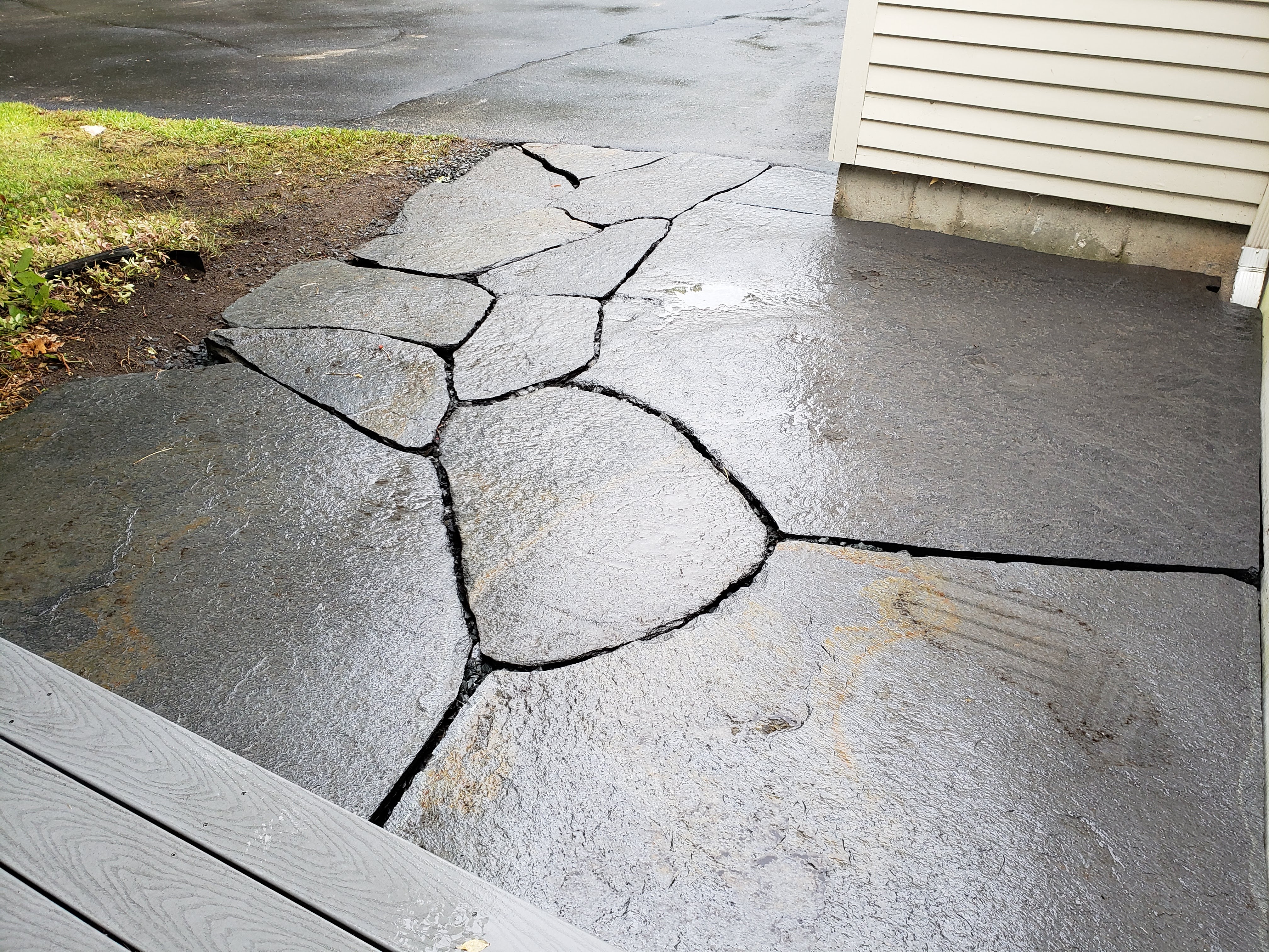Photo shows flat stone patio with gaps betweens stones.