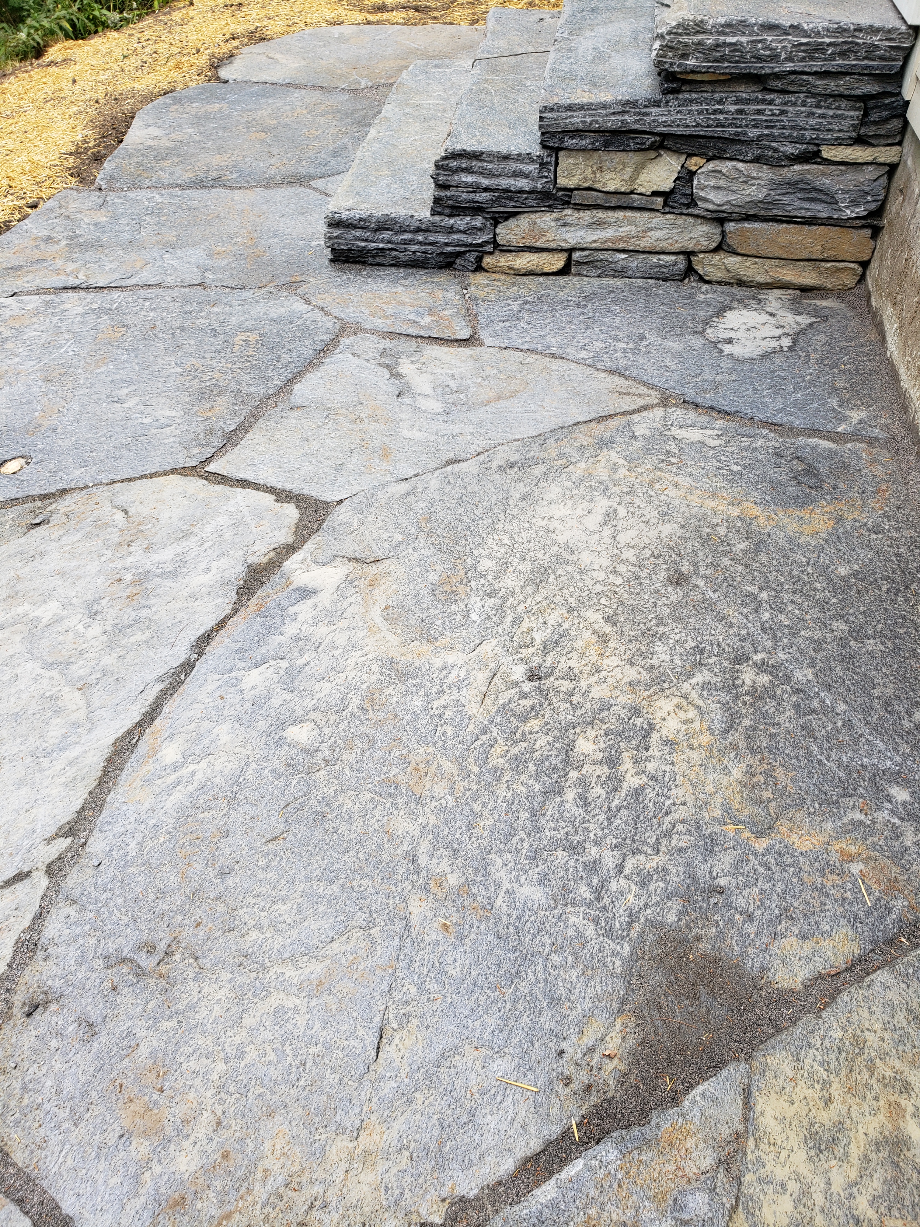 Photo shows flat-stone patio and stone steps from the side with many small pieces.