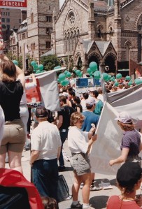 Photo from 1986 shows a group of people with balloons and banners by Boston's Arlington Street Church at Boston's Pride Parade