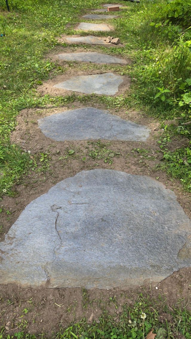 Photo shows a line of flat gray stones set into grass.