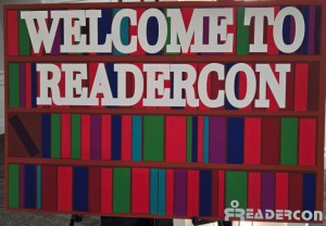 Multicolored sign with white text reading Welcome to Readercon and the Readercon logo in the lower right corner